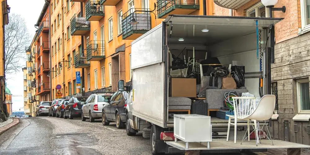 Flyttbil lastad med möbler och hushållsprylar parkerad på bostadsgata.