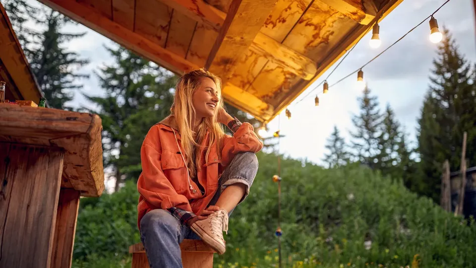 Kvinde sidder under pavillion med udsigt over skov.
