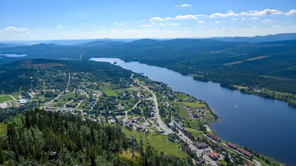 Flygfoto över en Funäsdalen och Funäsdalssjön, omgiven av skogsbevuxna kullar.