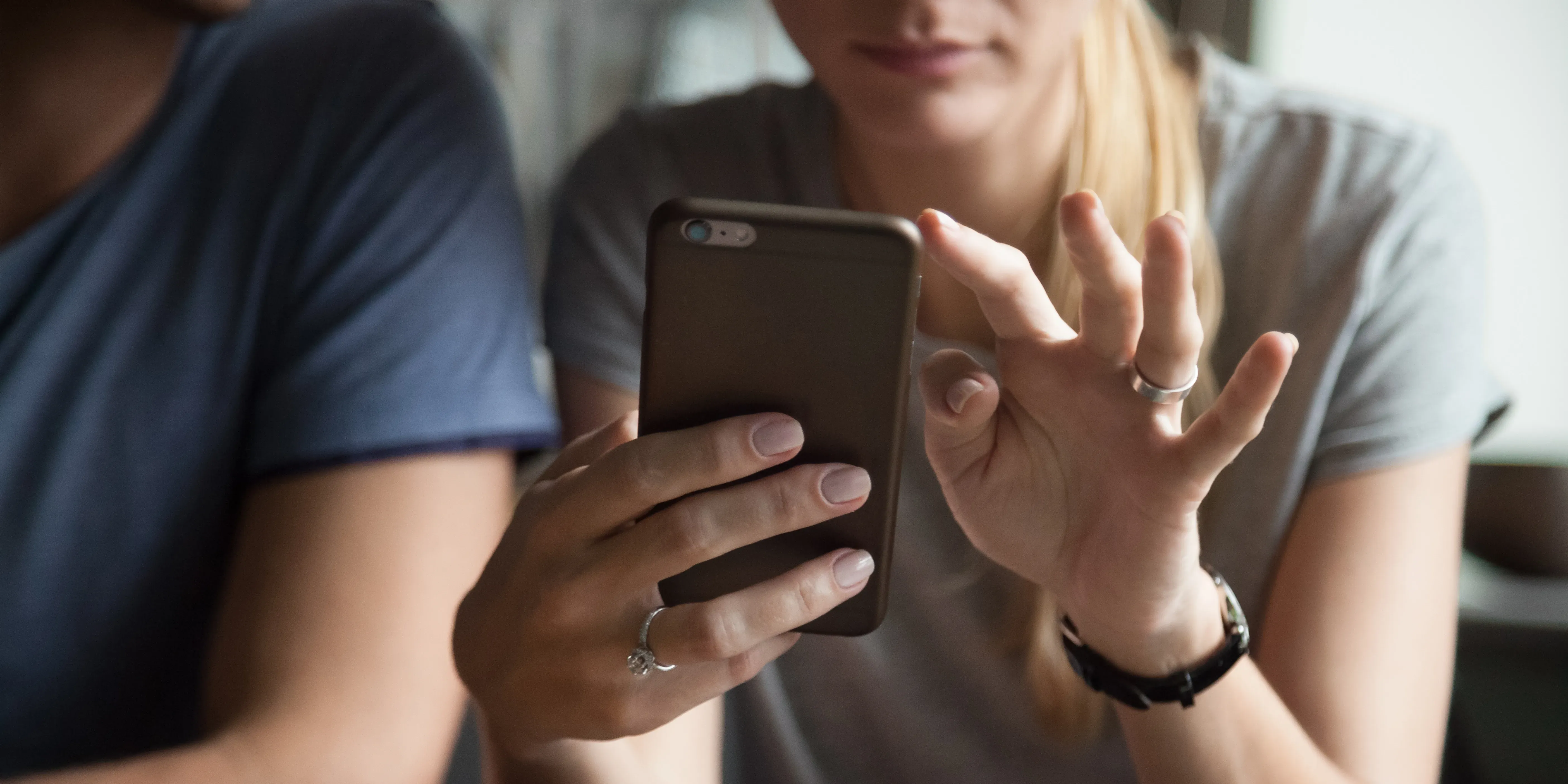 Et par ser på mobilen til en kvinne etter at hun har fått et bud før visning.