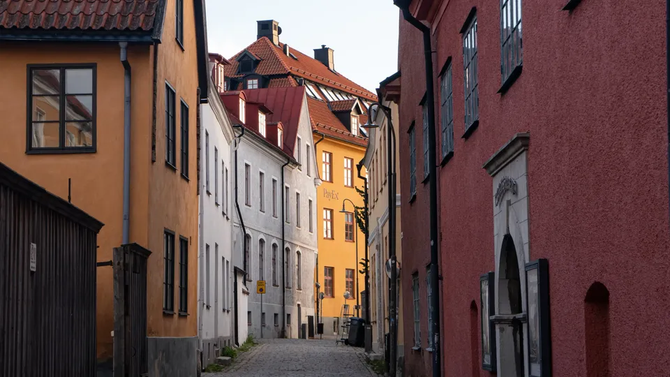 Smal kullerstensgata omgiven av färgglada historiska byggnader på Gotlands.