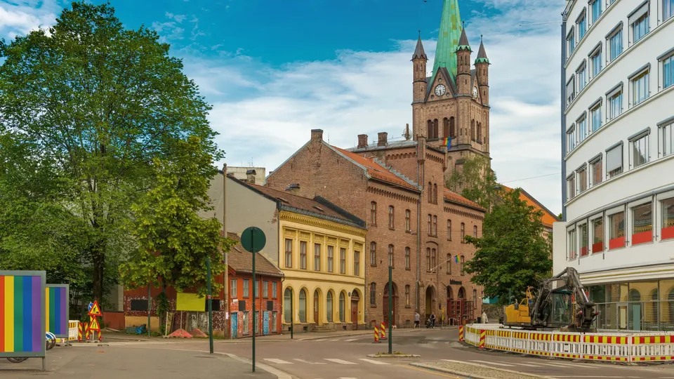 Urbant torg med historisk mursteinskirke og fargerik gatekuns på Grønland i Oslo.