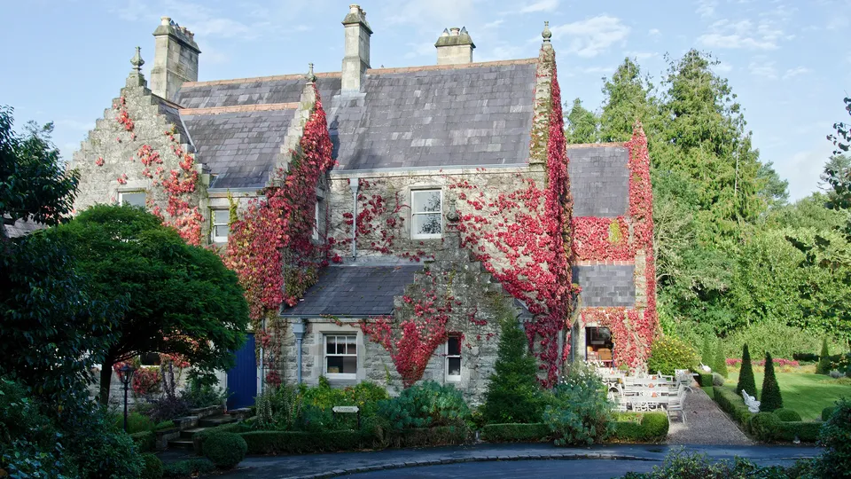 Solar panel installations. County Monaghan: Stone house covered in red ivy with manicured gardens.
