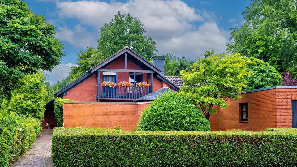 Backsteinhaus hinter einer Hecke in Hamburg-Wilhelmsburg