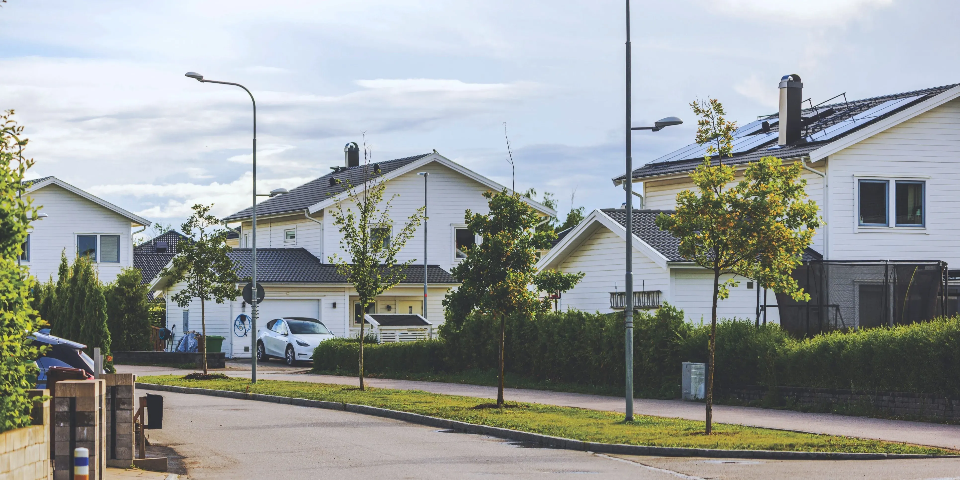 Ett svenskt bostadsområde med nybyggda vita hus, några med solpaneler på taken.