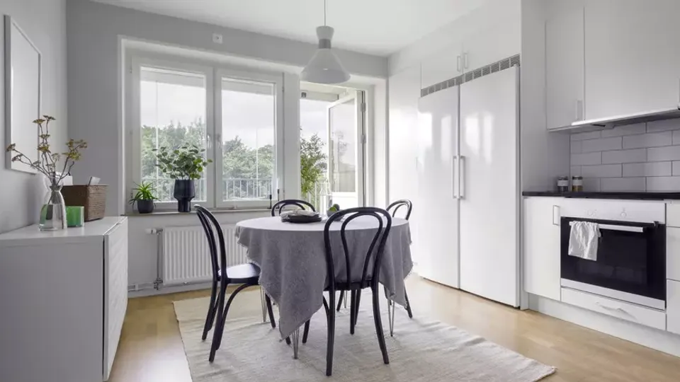 Modernt kök och matsal med runt bord och svarta stolar.