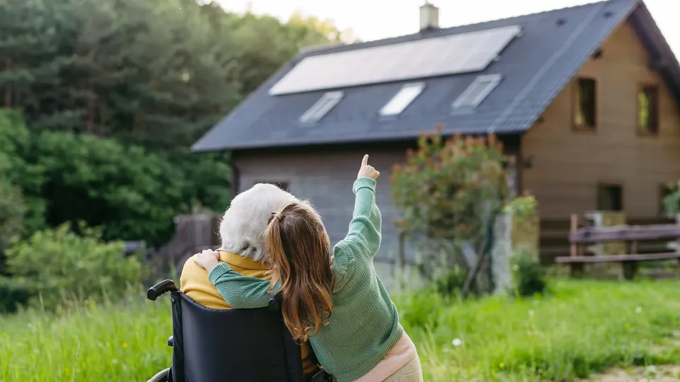 Grandmother and grandchild looking up at solar panels on a rooftop