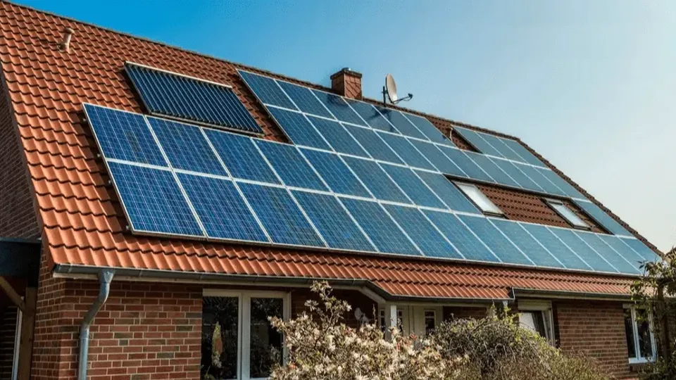 Brick house with solar panels installed on orange tile roof.