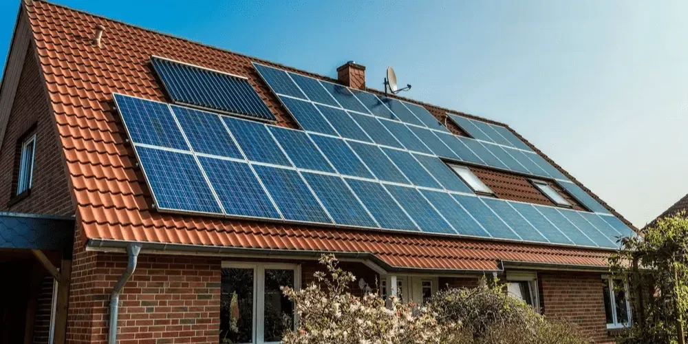 Brick house with solar panels installed on orange tile roof.
