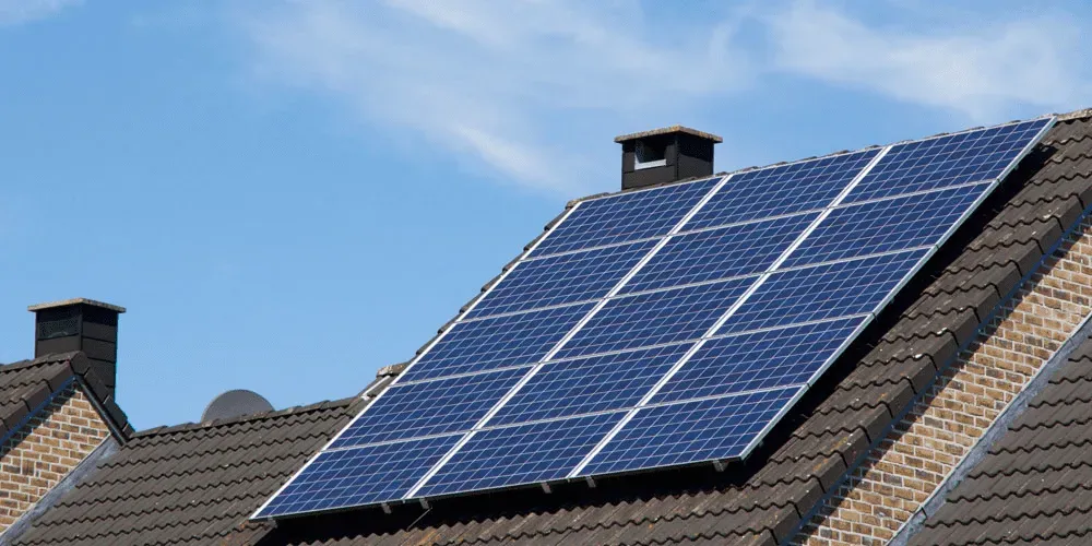 Solar panels installed on a residential roof under blue sky produce electricity
