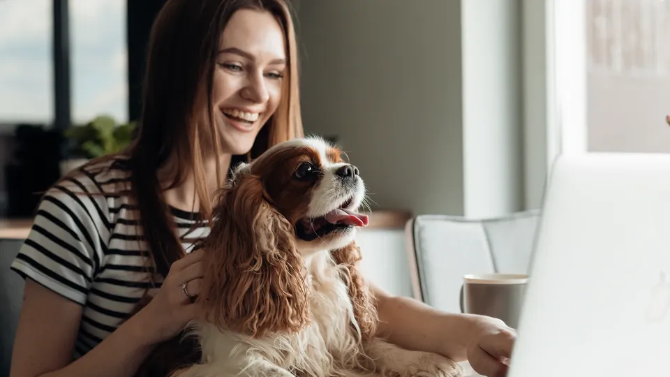 Kvinde smiler mens hun holder en lille hund.