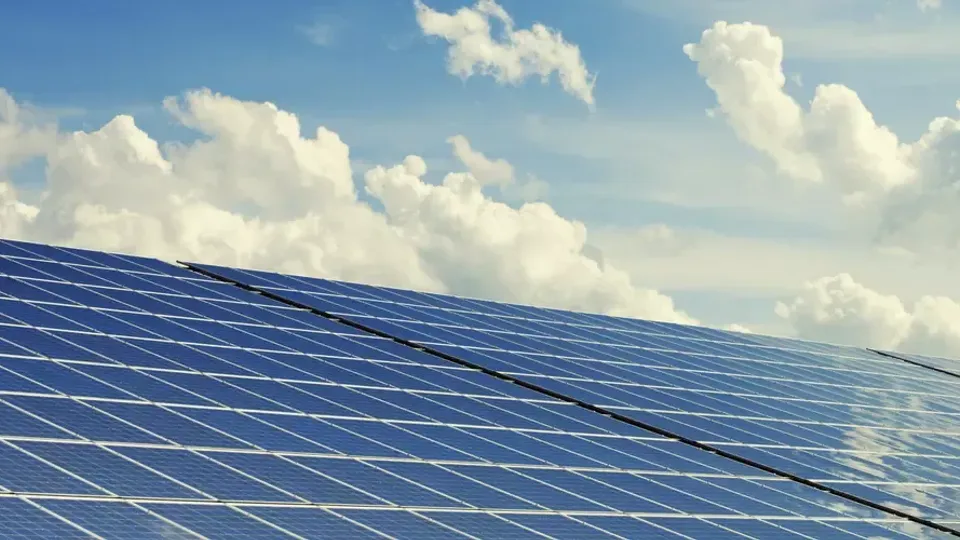 Solceller på ett tak framför en himmel med vita moln.