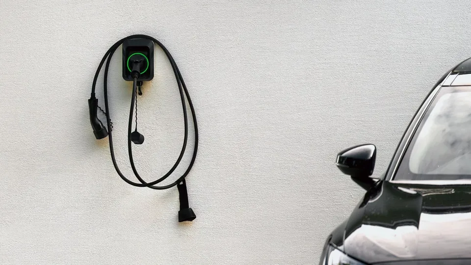 Bilde av en ladeboks og en elbil på siden