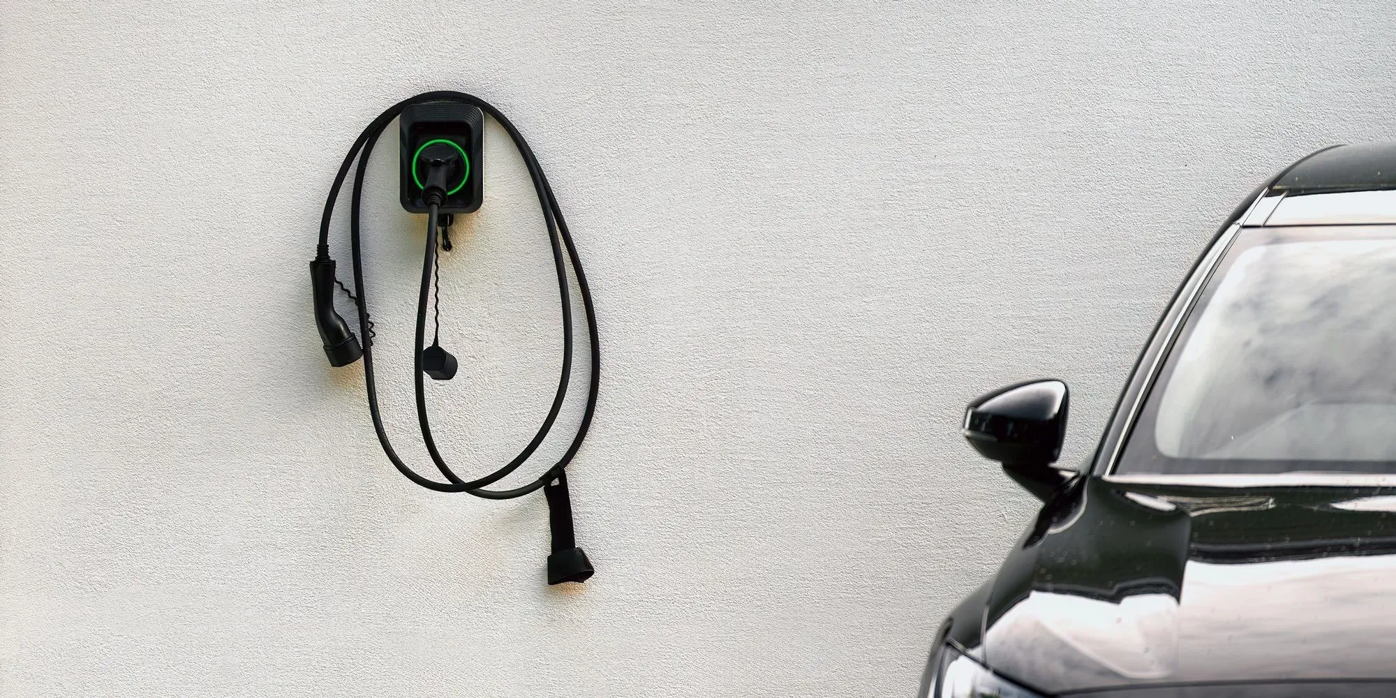 Bilde av en ladeboks og en elbil på siden