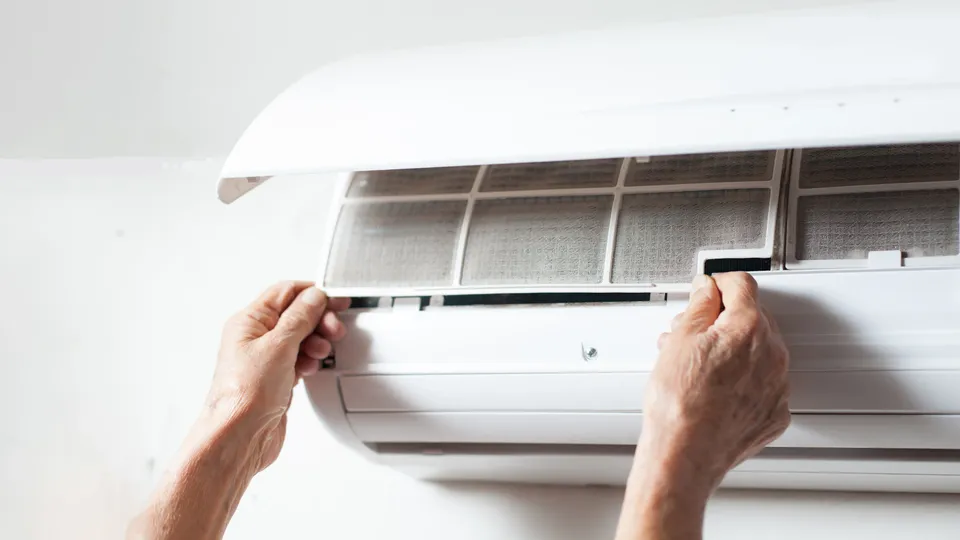 Person fjerner filterplate fra varmepumpe