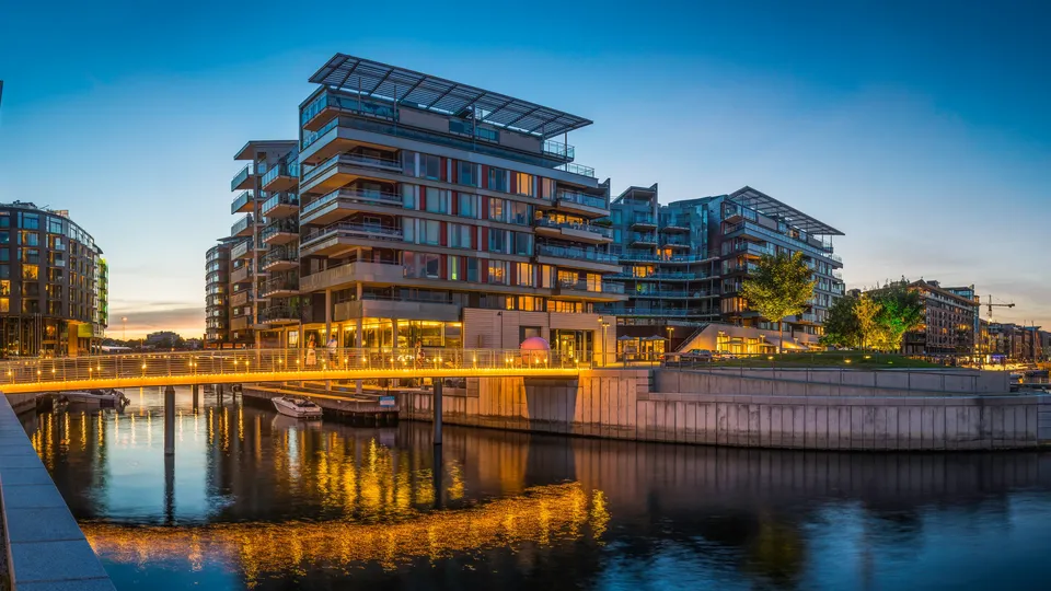 Moderne bygninger på Aker brygge langs Oslofjorden i skumringen.