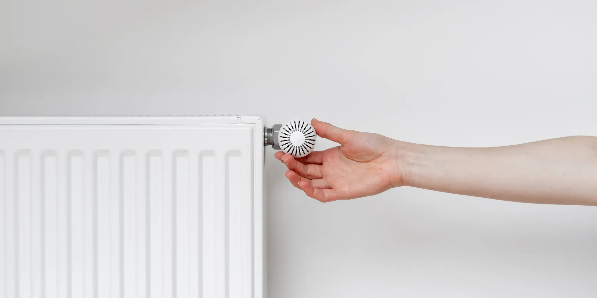 Hand adjusting a radiator thermostat valve.
