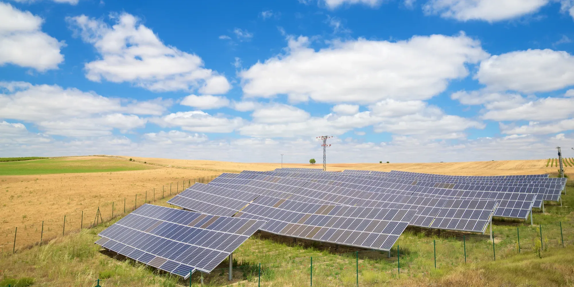 Matriz de paneles solares instalada en terreno agrícola rural bajo un cielo azul.