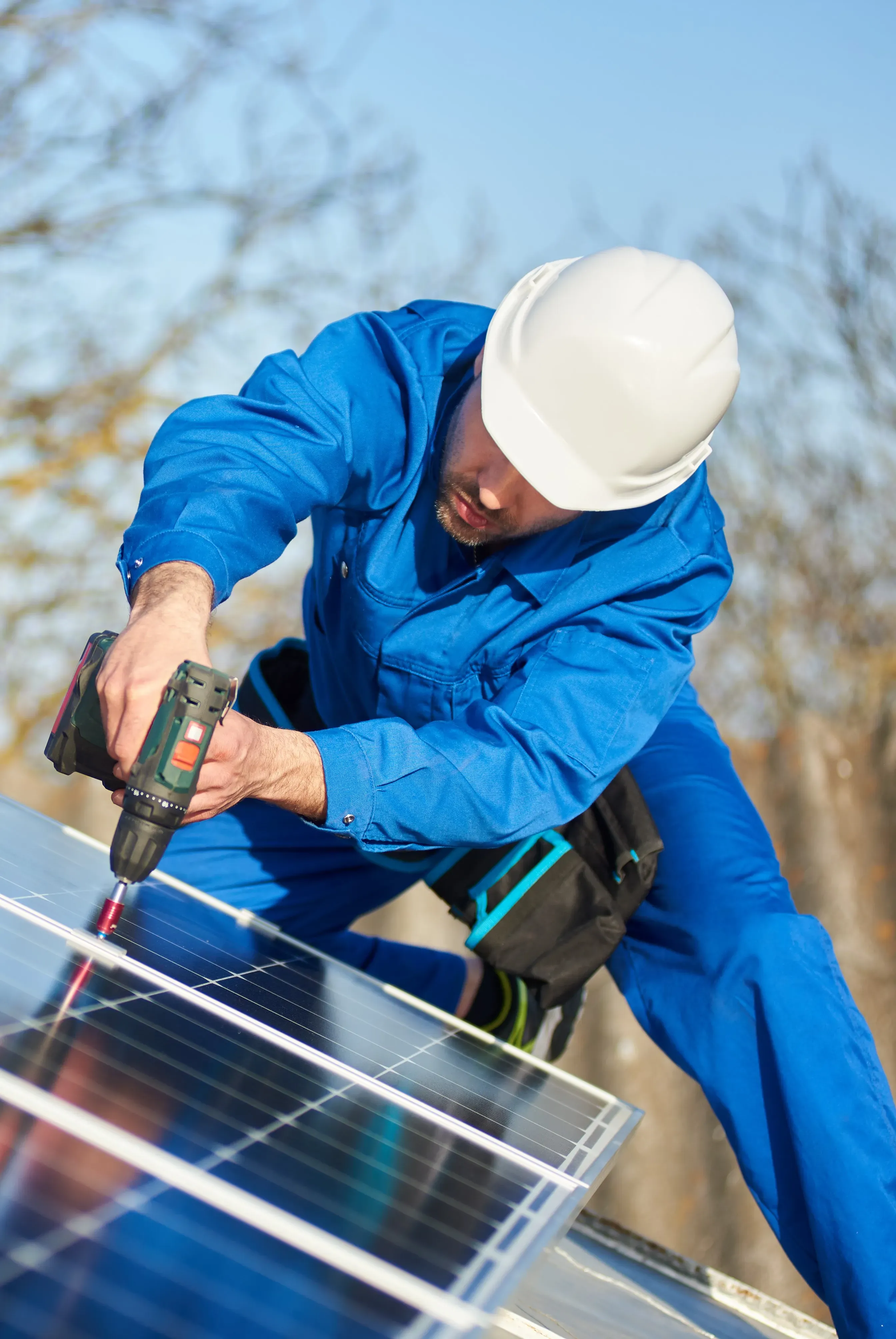 Trabajador instalando panel solar con taladro eléctrico.