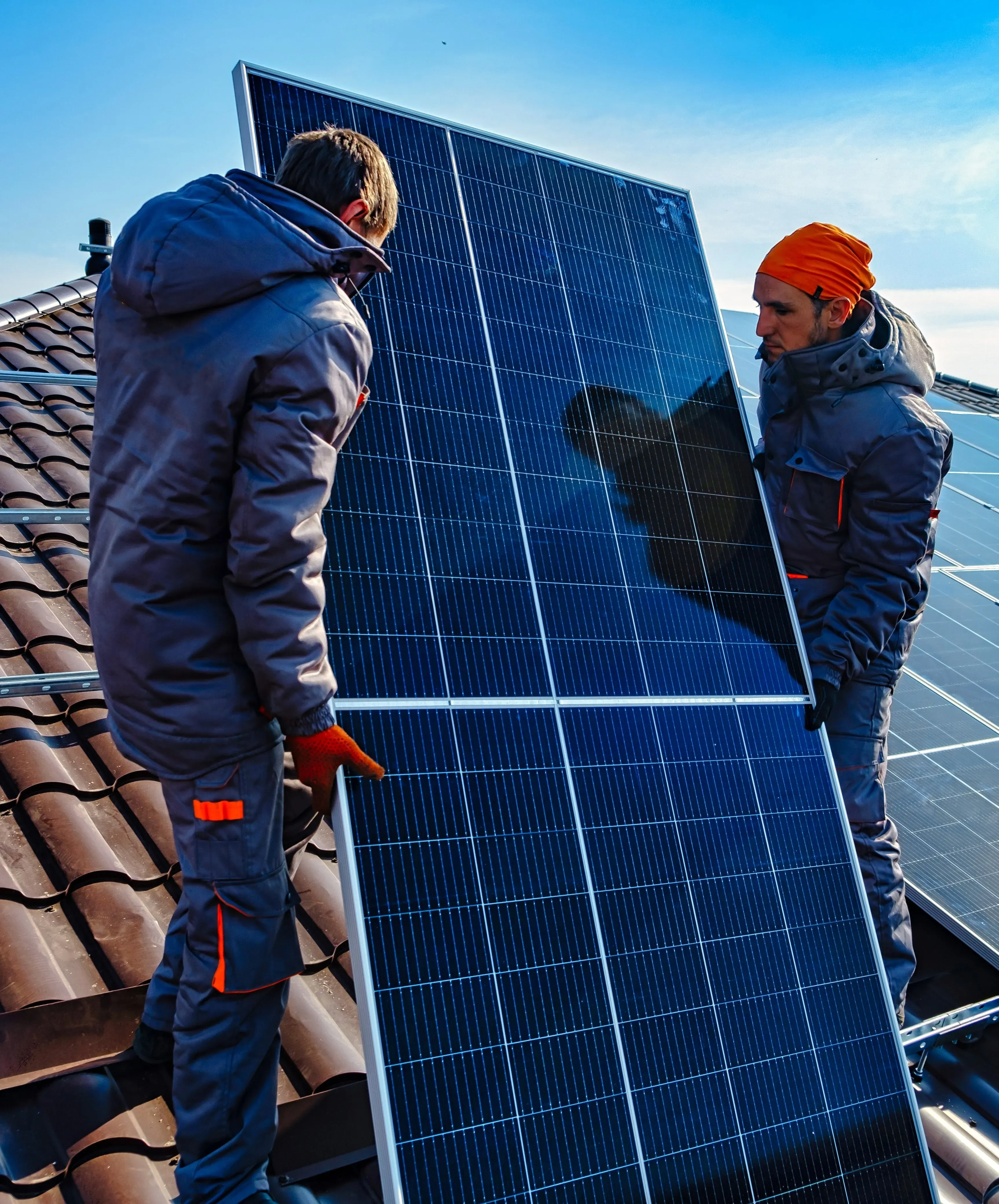 Dos trabajadores instalando un panel solar en un tejado.