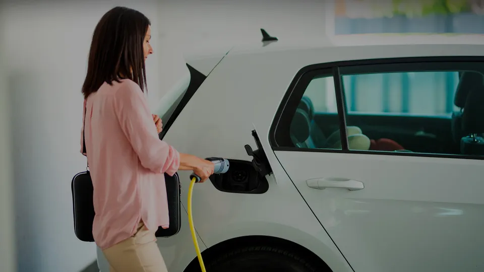 Woman using a charging cable to charge her EV