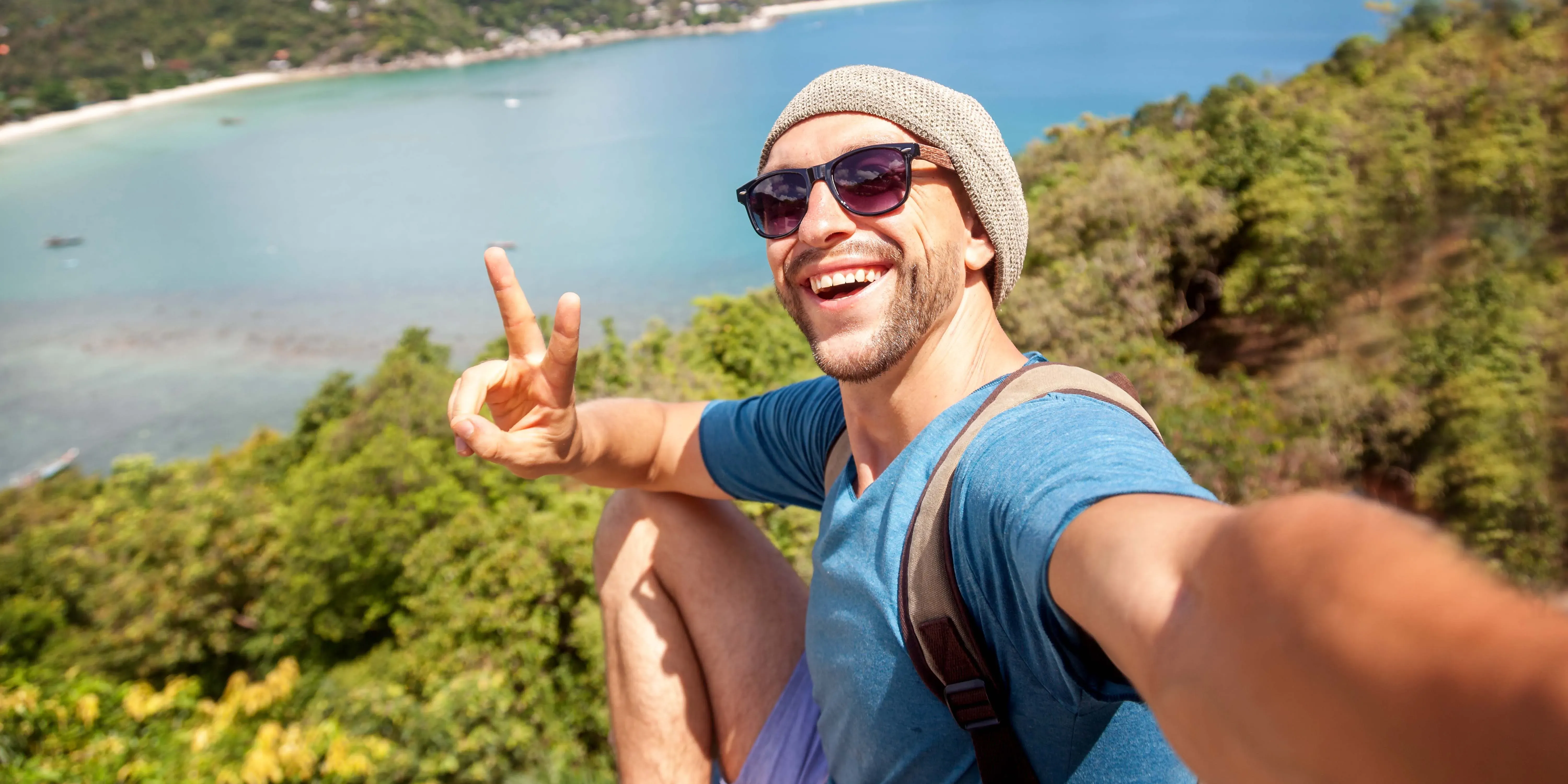 Hombre tomándose una selfie en un mirador costero haciendo el signo de paz.