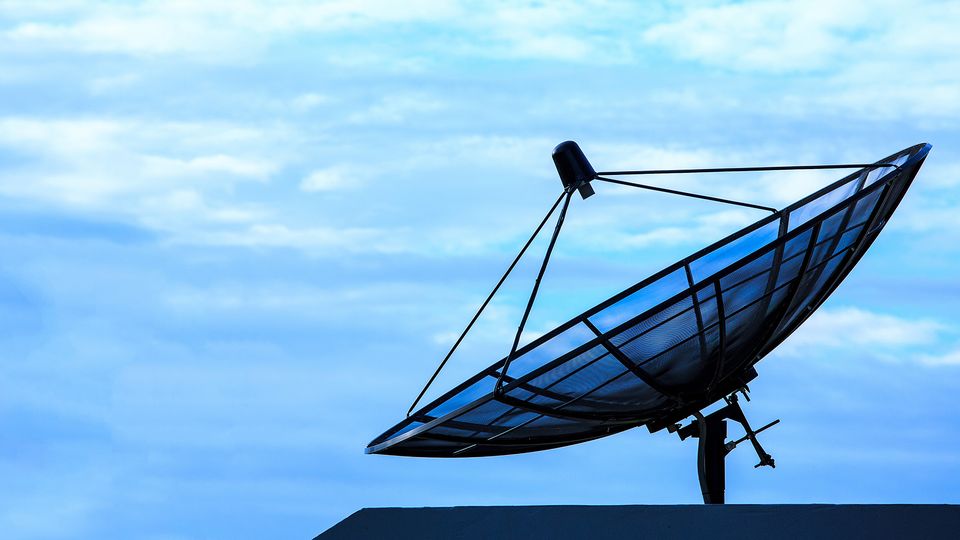 Bilde av en satellittantenne med blå himmel i bakgrunnen.