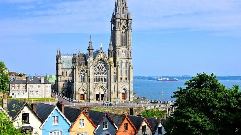 Colorful houses in front of a tall cathedral overlooking the water in Cork.