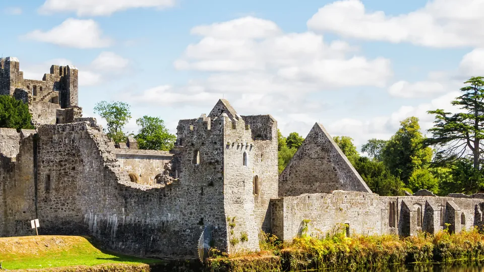 Stone castle ruins along a calm river.