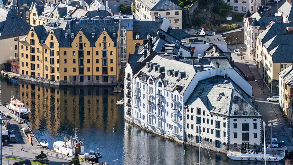 Luftfoto av fargerike bygninger langs en smal kanal med fortøyde båter.