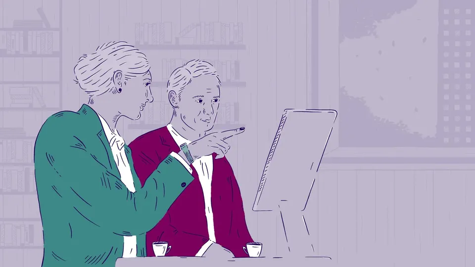 En kvinde peger på en computerskærm ved siden af en mand.