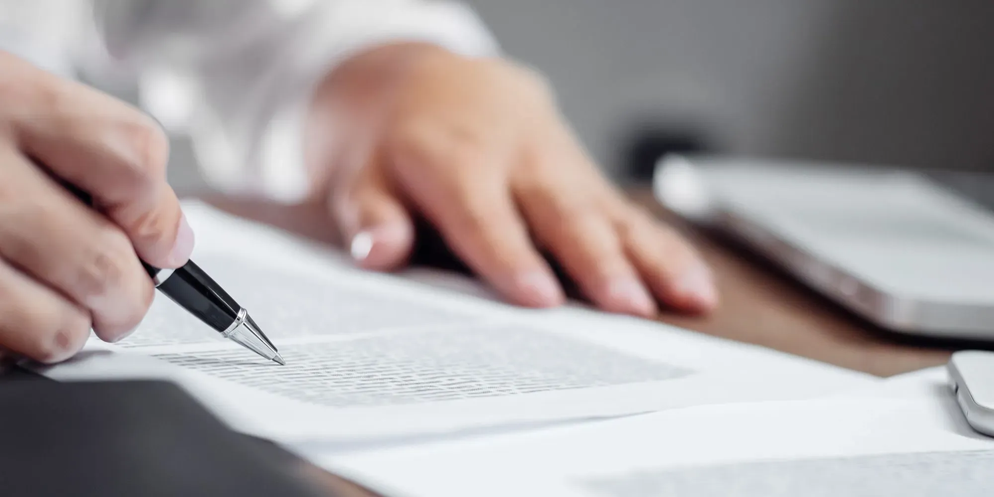 Nærbilde av en person som finleser og signerer papirer