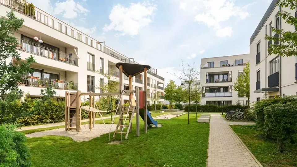 Modern bostadsgård med trälekverk och grön gräsmatta.