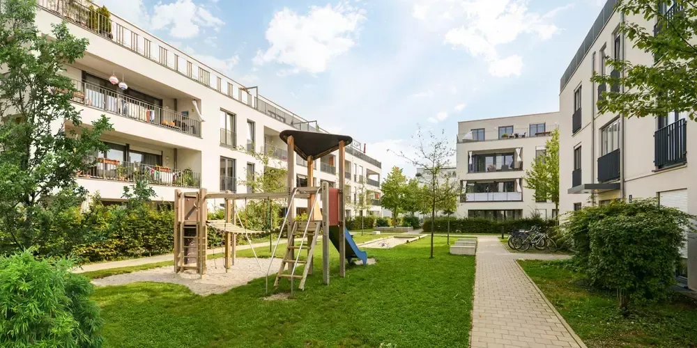 Modern bostadsgård med trälekverk och grön gräsmatta.