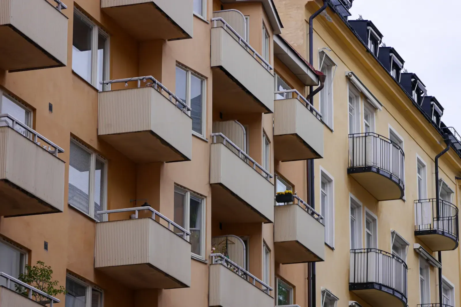 Modernt lägenhetshus med förskjutna balkonger och blandade fasadfärger.
