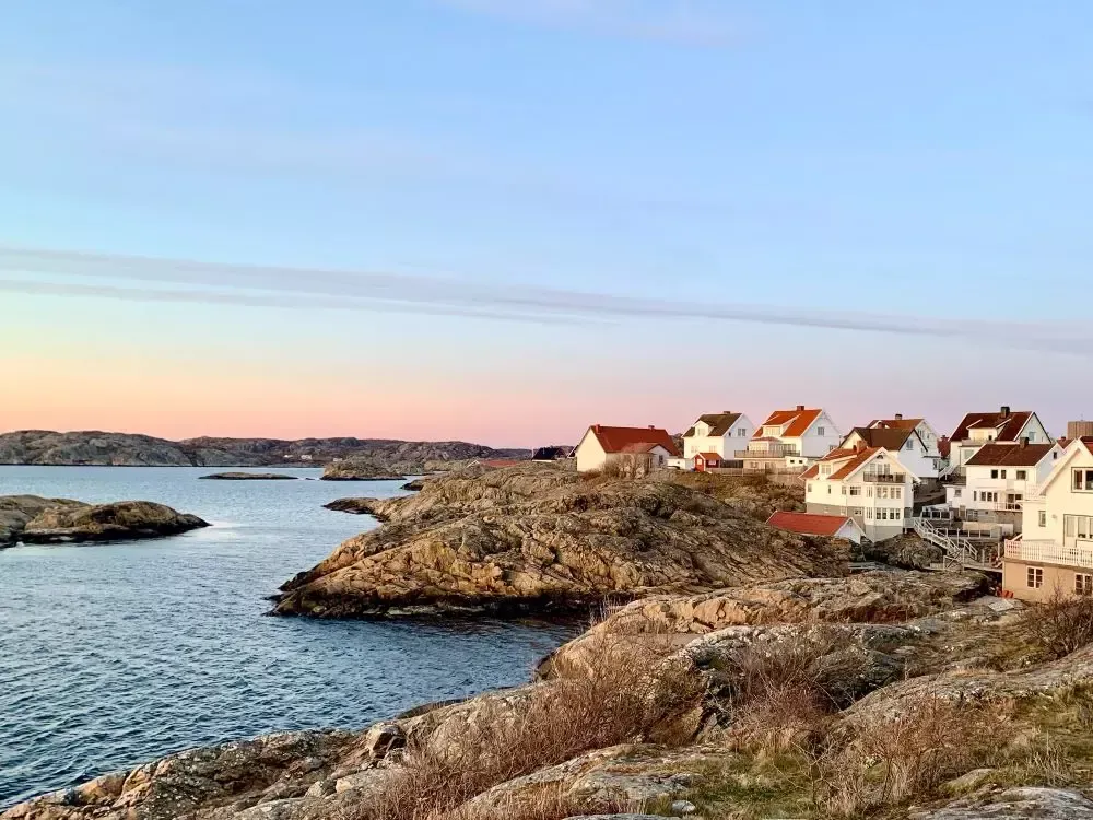 Vita sommarhus på Västkusten med klippor som tomt.
