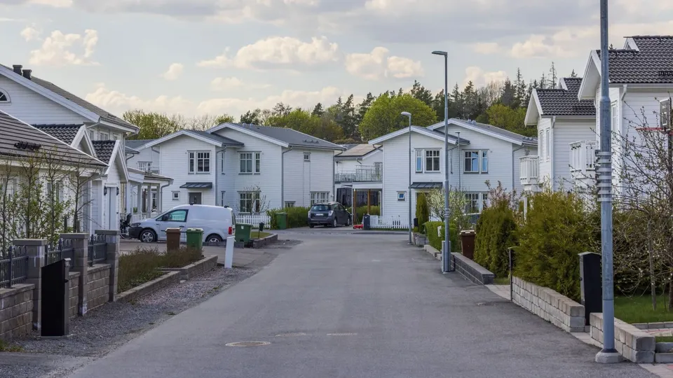 Bostadsgata med vita hus och parkerade bilar.