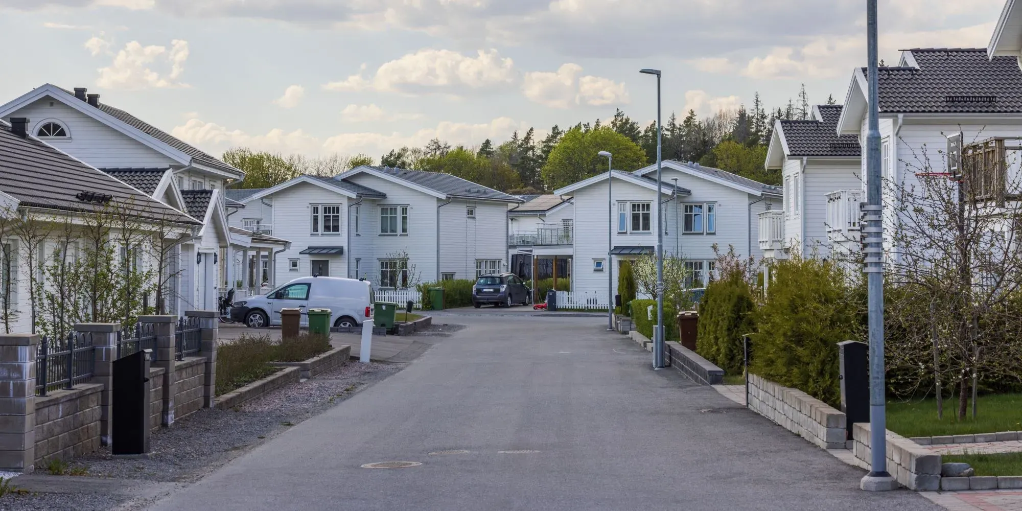Bostadsgata med vita hus och parkerade bilar.