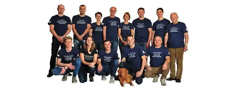 Team von Lainer Installationen posiert zusammen mit einem Hund.
