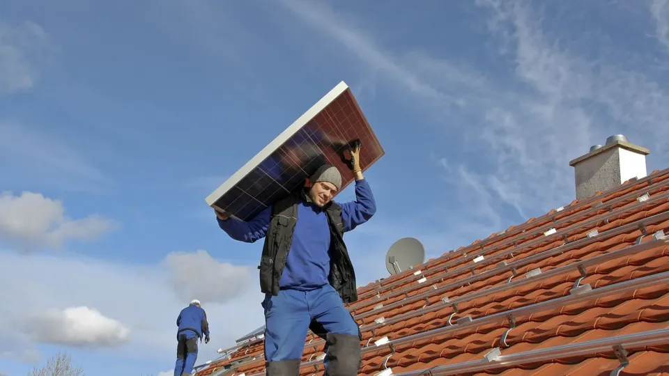 Solcellemontør løfter solceller, fordi han er ved at installere dem på taget
