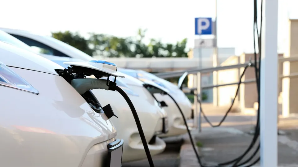 Elektriske køretøjer oplades ved en parkeringsstation med opladningskaber tilsluttet.