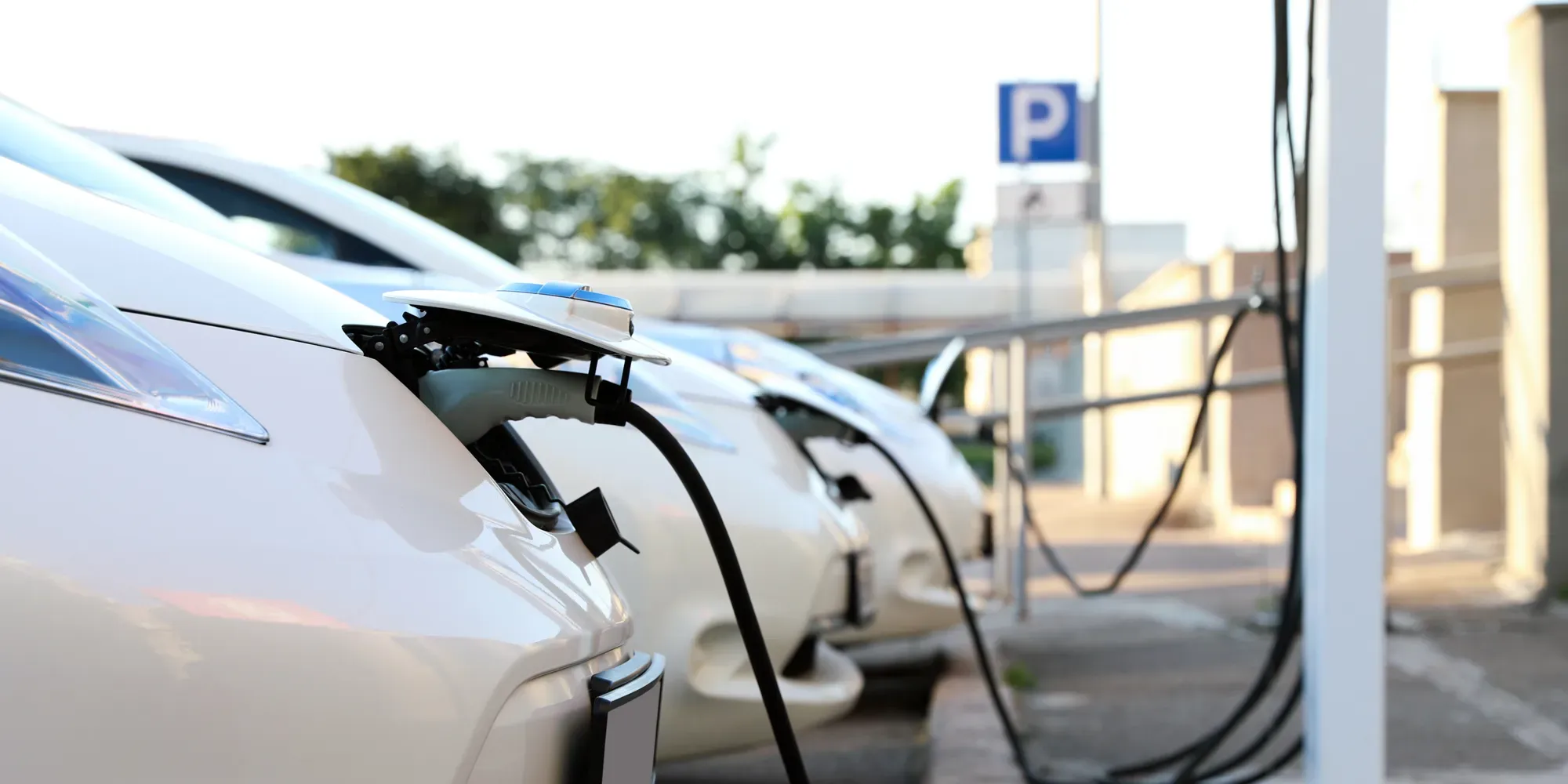 Elektriske køretøjer oplades ved en parkeringsstation med opladningskaber tilsluttet.