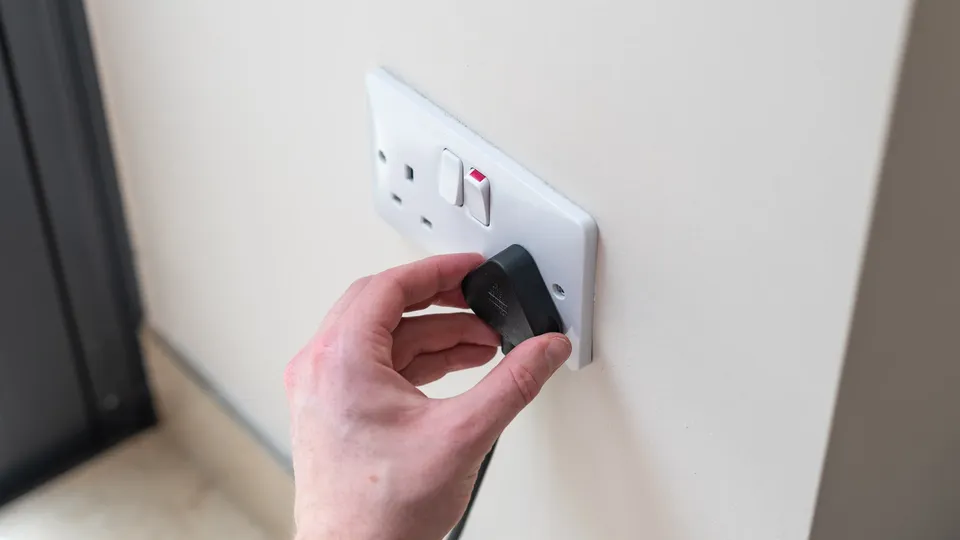 A person plugging a pug into a outlet