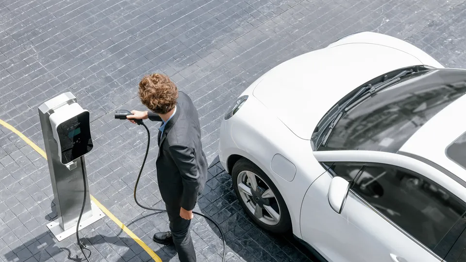 Birdseye view of a man charging a white electric car.