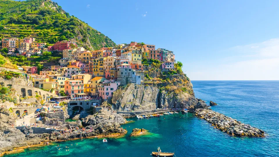 Villaggio colorato sulla scogliera con barche in acqua mediterranea turchese.