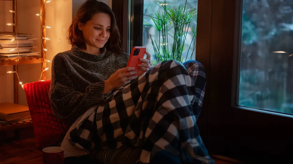 Kvinde slapper af i hjemmet med sin telefon