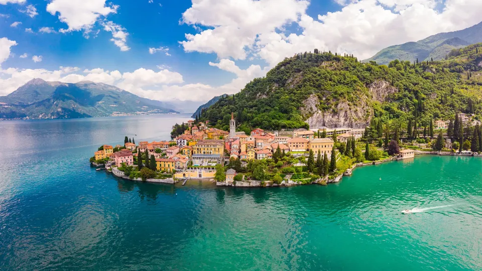 Villaggio colorato sulla riva circondata da lago turchese e montagne.
