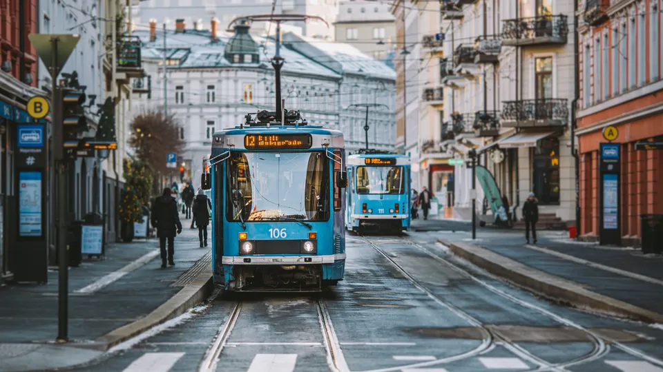 Blå trikk som kjører på skinner gjennom en gate på Majorstua i Oslo.