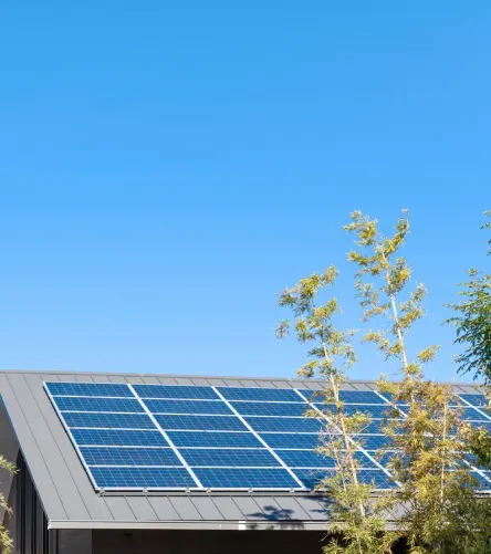 Paneles solares instalados en el techo de una casa bajo cielo azul despejado.