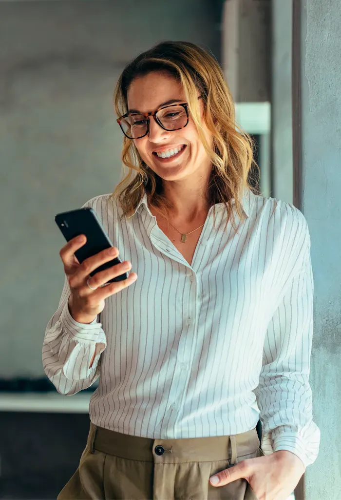 Mujer sonriendo mientras mira el smartphone.